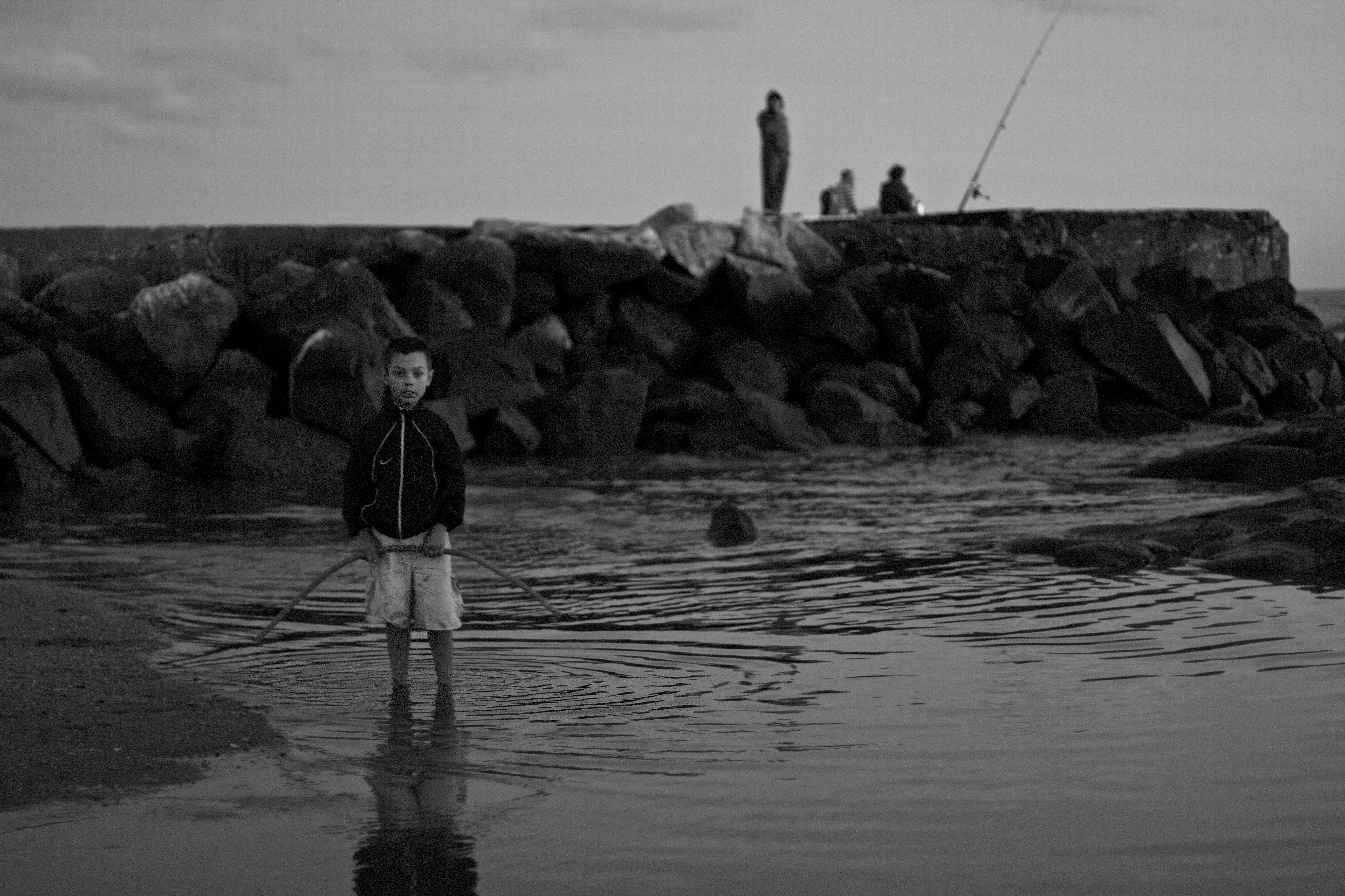 Niño en la playa con pescadores.